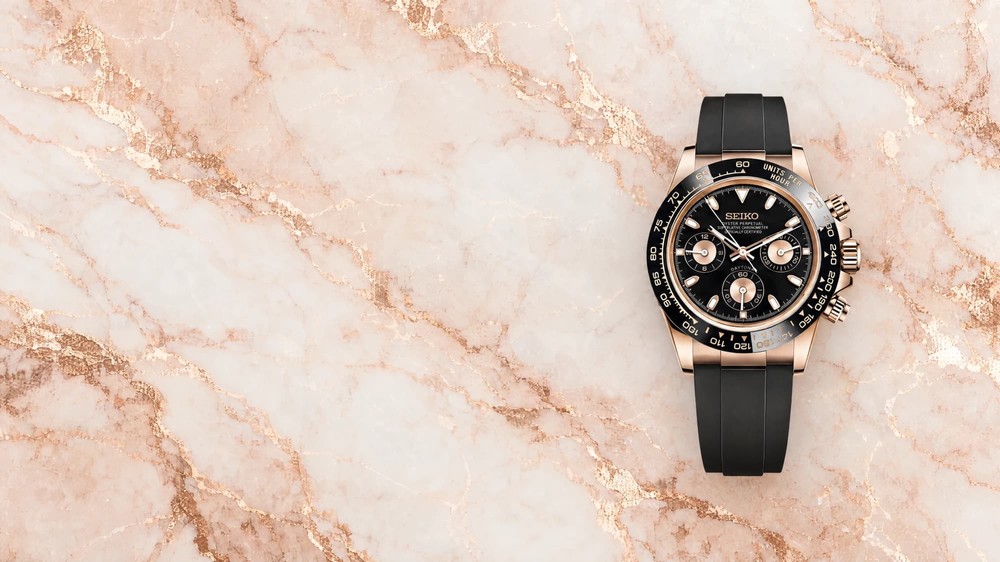 The Seitona, a rose gold-tone chronograph on a black rubber strap, lying on pink marble
